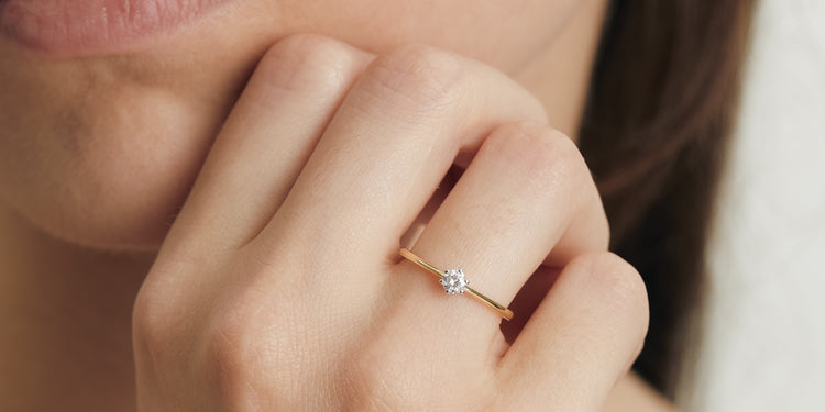 Zarter Goldring mit Solitär-Diamant am Finger getragen