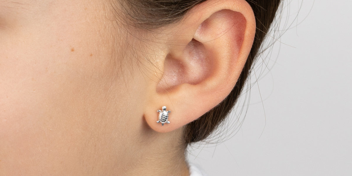 Silberner Ohrstecker mit Schildkröten-Motiv am Ohr getragen